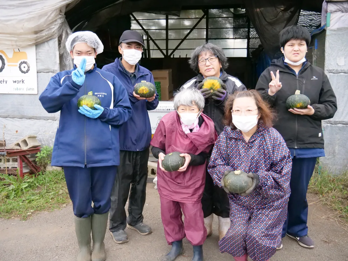 作業場の入口でかぼちゃを持つ6人