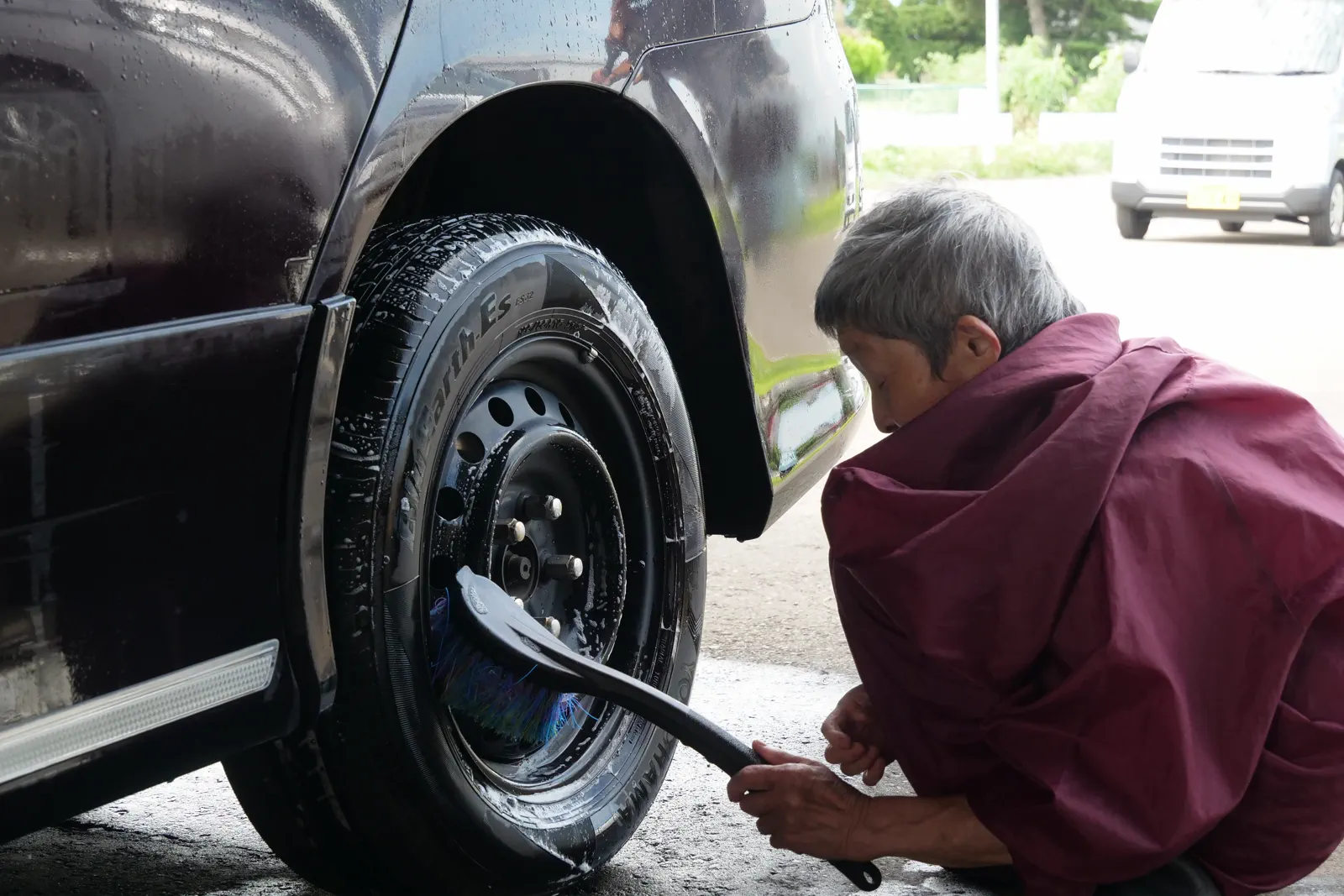 黒い車のタイヤをブラシで洗う手元